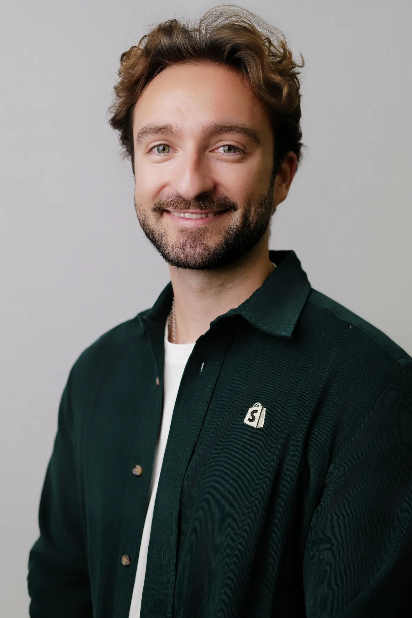 Studio headshot of a smiling man in a dark green shirt